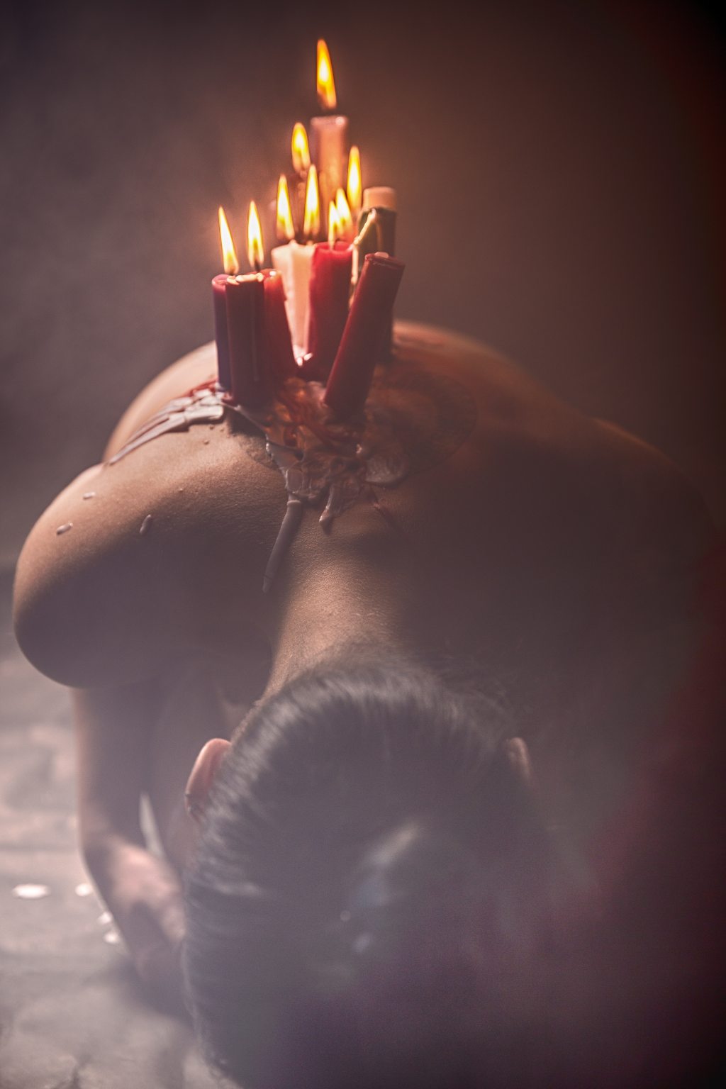 photo of womans back with burning candles and wax dripping on her back