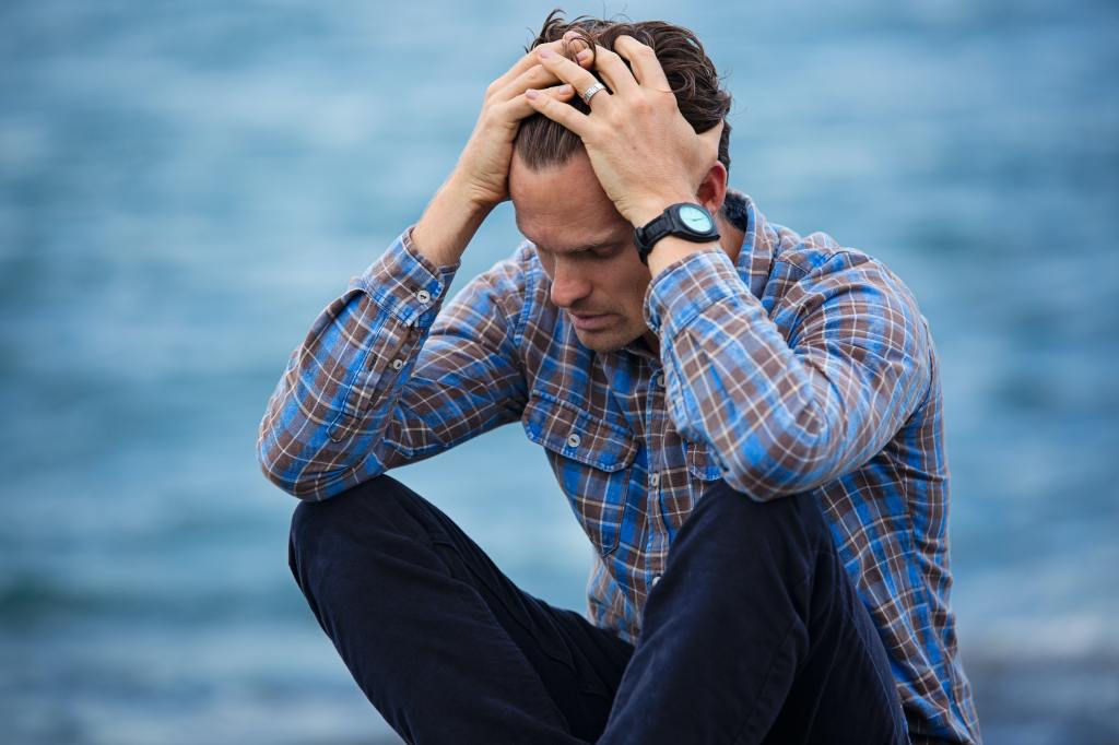 Man in blue shirt holding his head in frustration