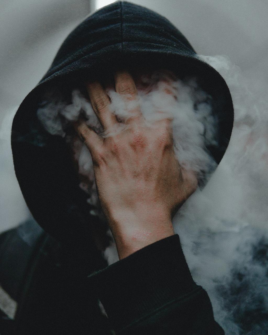 Photo of a man holding his hand over his face with smoke