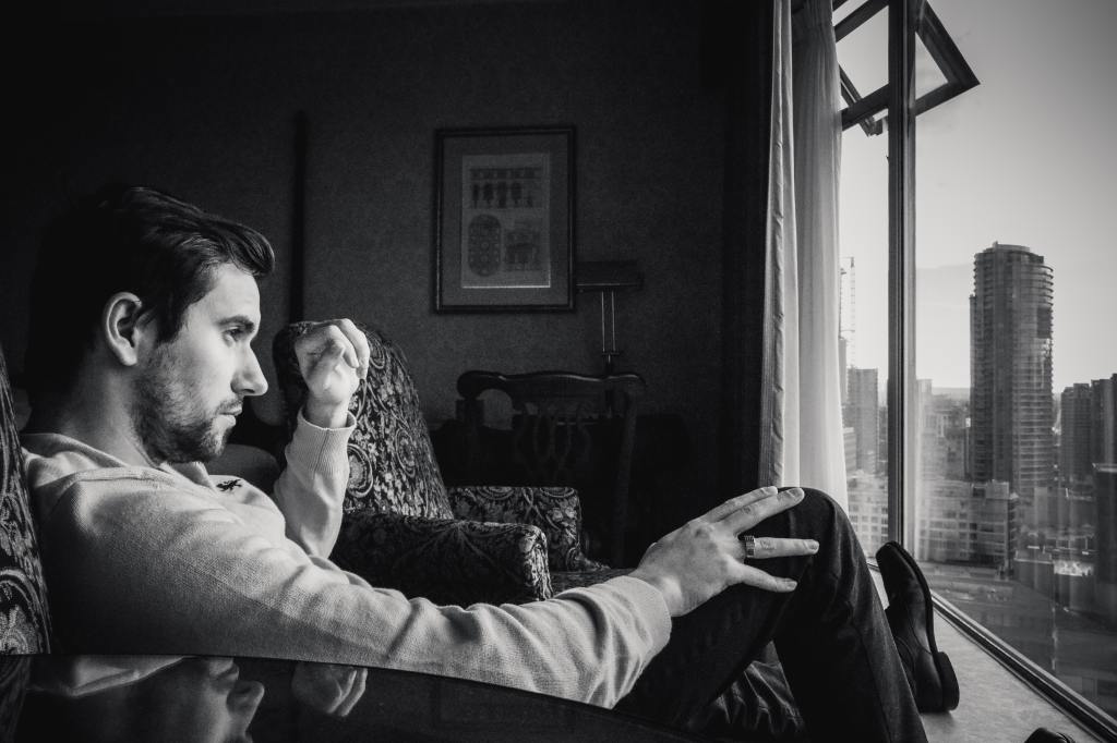 Grayscale Photo of Man Looking at Window