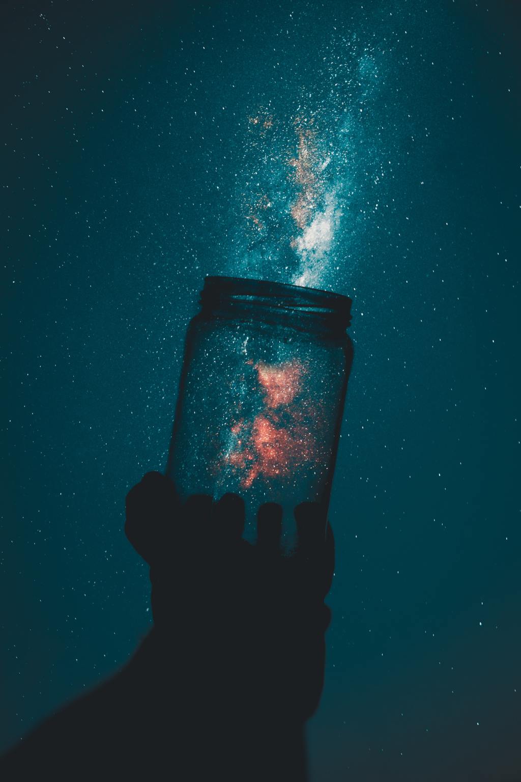 Photo of a silhouette of person holding glass mason jar