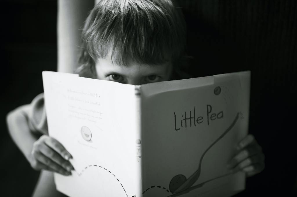 Child peering over a book
