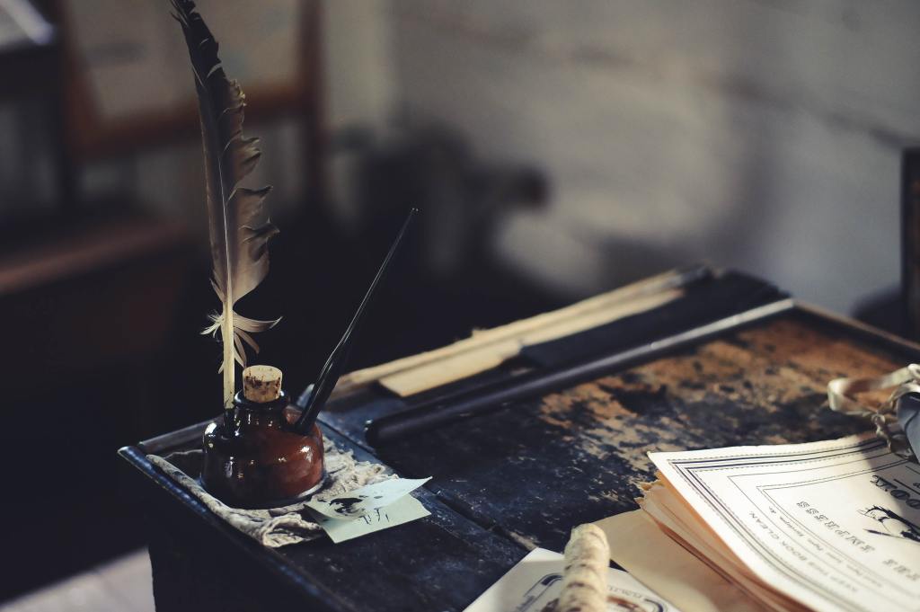 Feather with inkwell on old wooden desk
