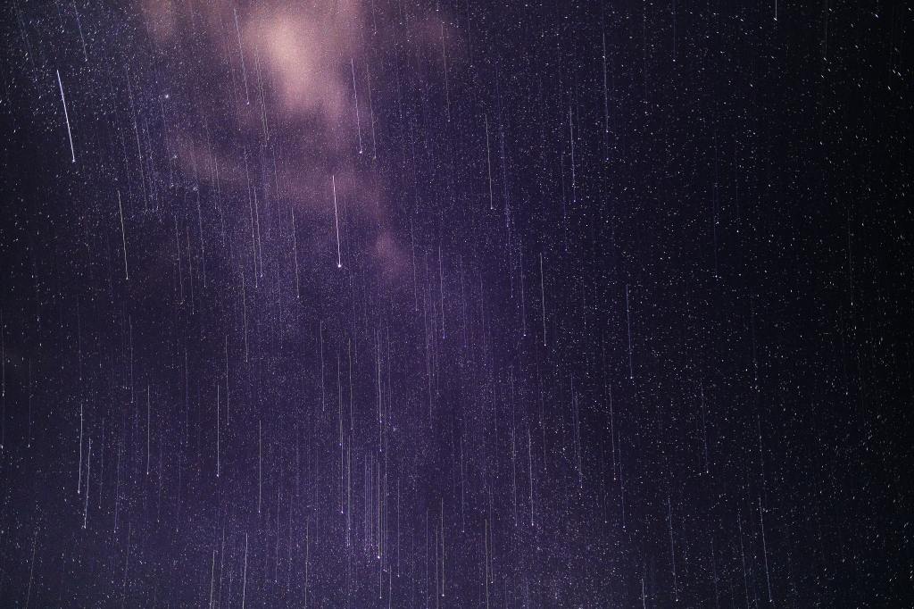 A lot of meteors or "falling stars" in a bright purple starry sky.