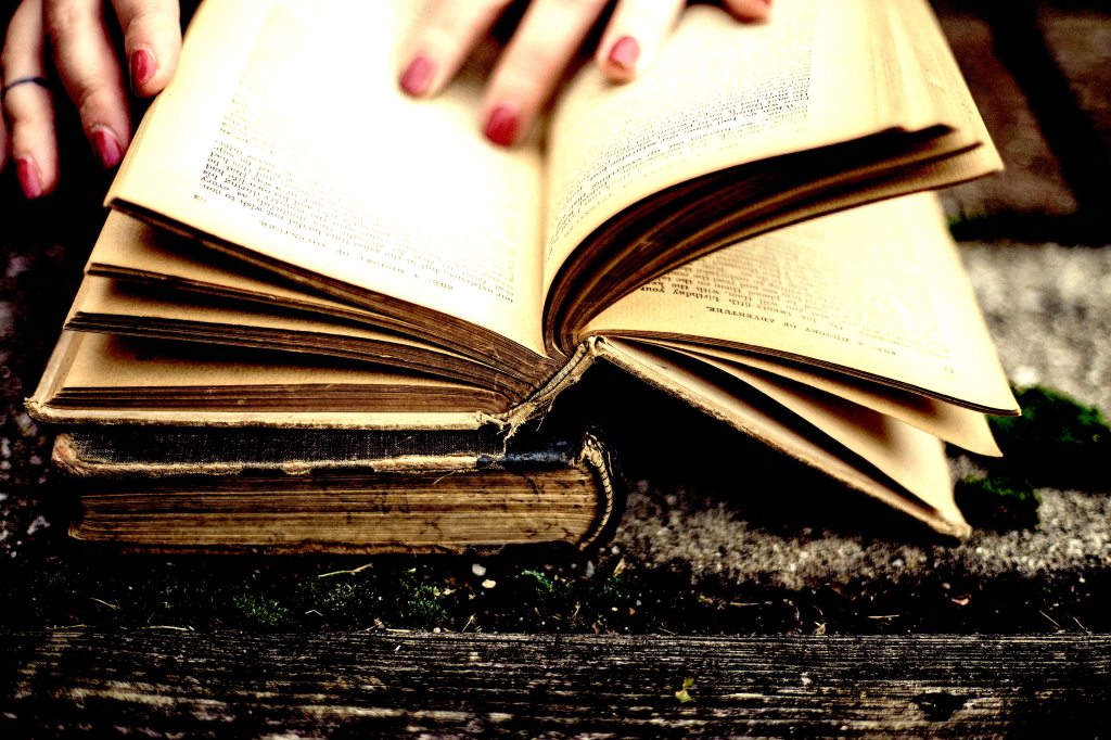 Fingers with red nail polish thumbing through pages of a book