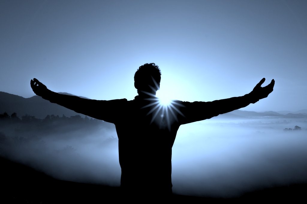 man standing on mountain during sunrise with his arms extended